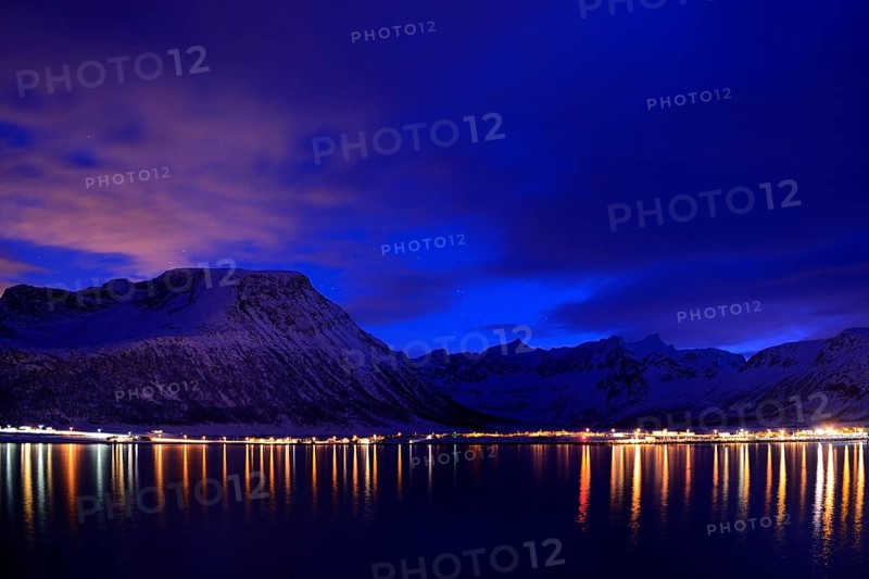 Reflection of lights in the fjord with mountains the blue hour