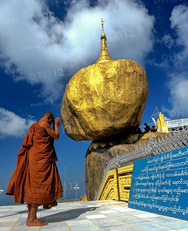 Buddhist Monk praying in front of the Golden Rock or Kyaiktiyo Pagoda