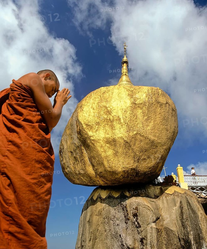 Buddhist Monk praying in front of the Golden Rock or Kyaiktiyo Pagoda