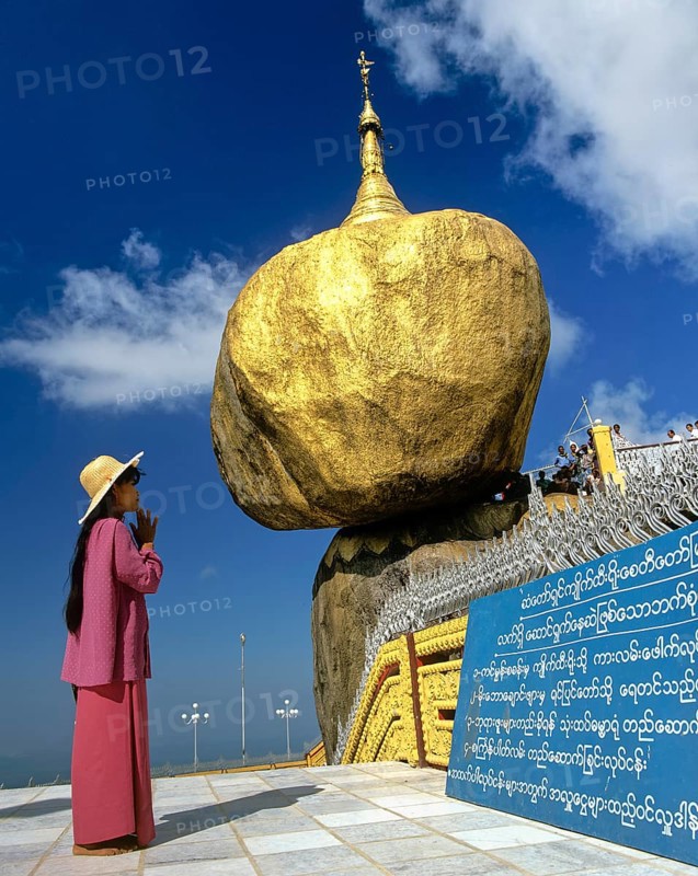 Woman praying in front of the Golden Rock or Kyaiktiyo Pagoda