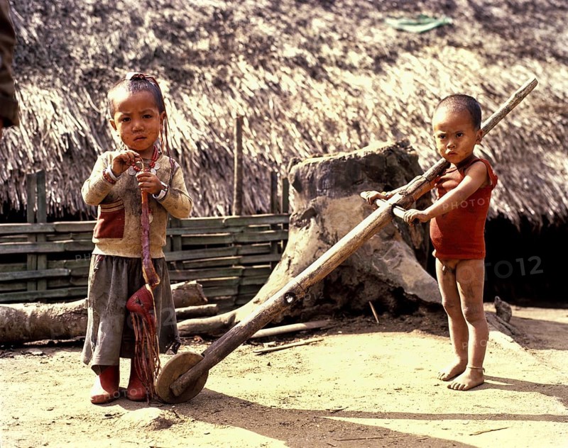 Akha boy and Akha girl in torn clothes with primitive toys