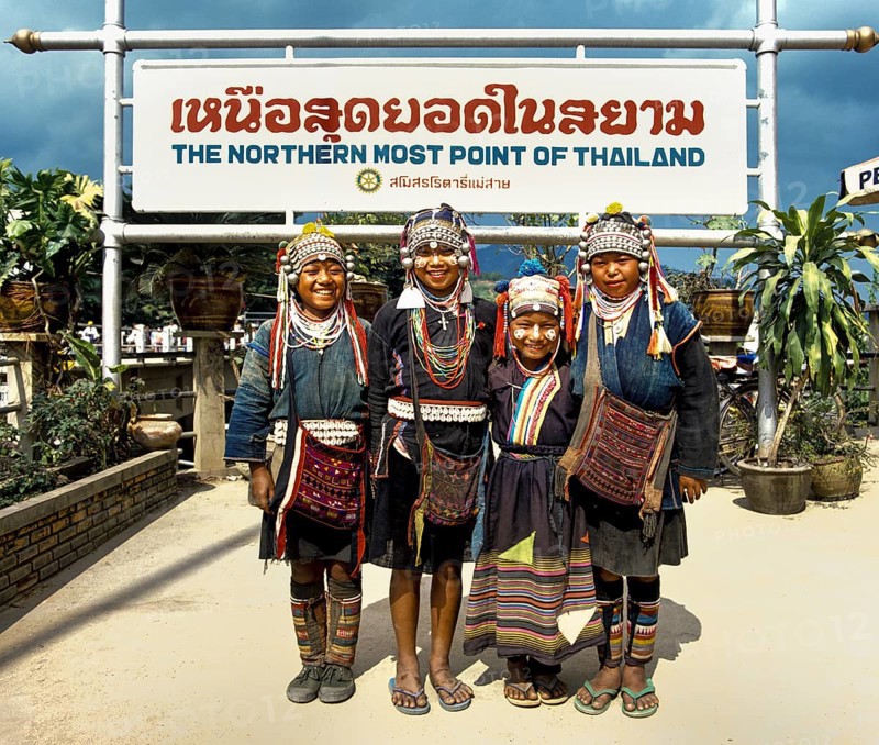 Akha hill tribe girls wearing traditional costumes and headdresses standing at the northernmost point of Thailand