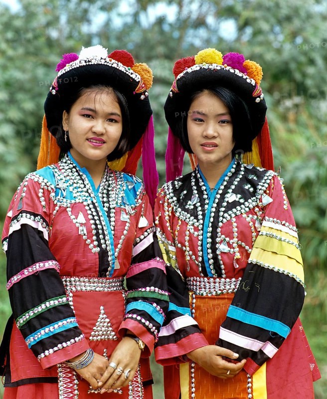 Two Lisu girls wearing colourful headdresses and the traditional costume of the mountain people