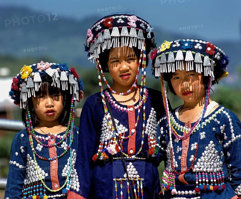 Three Lisu girls wearing colourful headdresses and the traditional costume of the mountain people