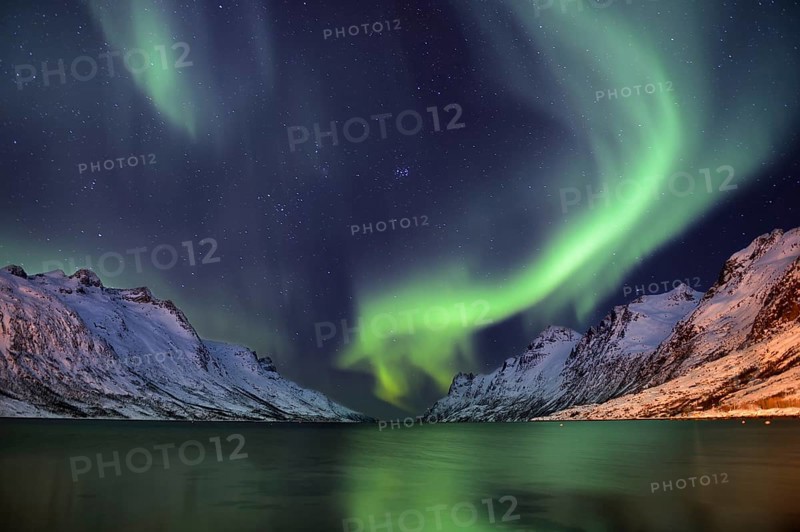 Aurora over a fjord with snow-covered mountains