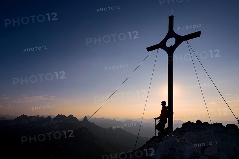 Mountaineer at the summit cross on Grosser Krottenkopf Mountain at dusk