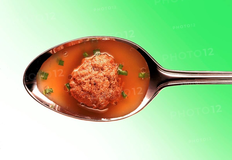 Meatball in broth on a silver spoon