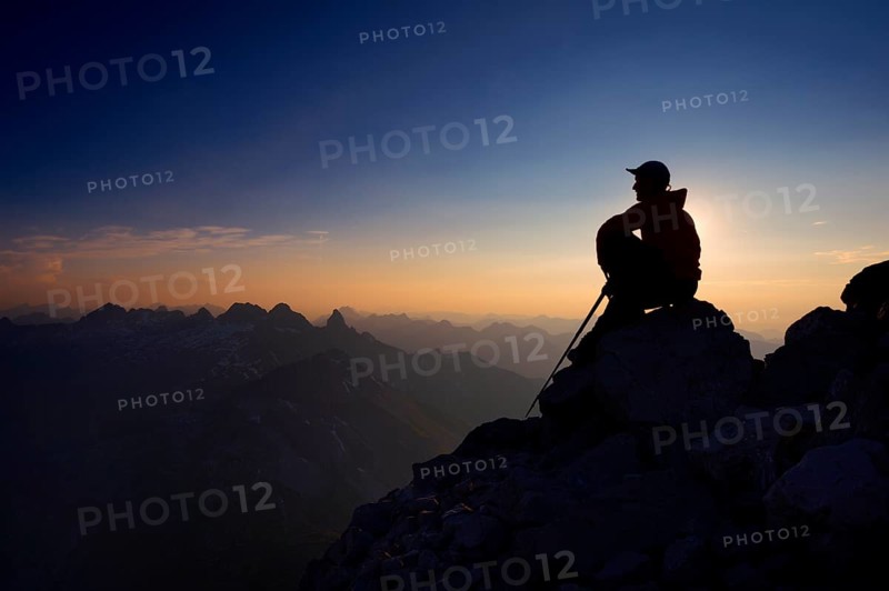 Mountaineer sitting on a rock on Grosser Krottenkopf Mountain at dusk