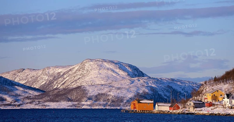 Fishing village beside a fjord with wintry mountains