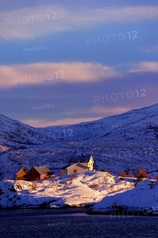 Fishing village beside a fjord with wintry mountains
