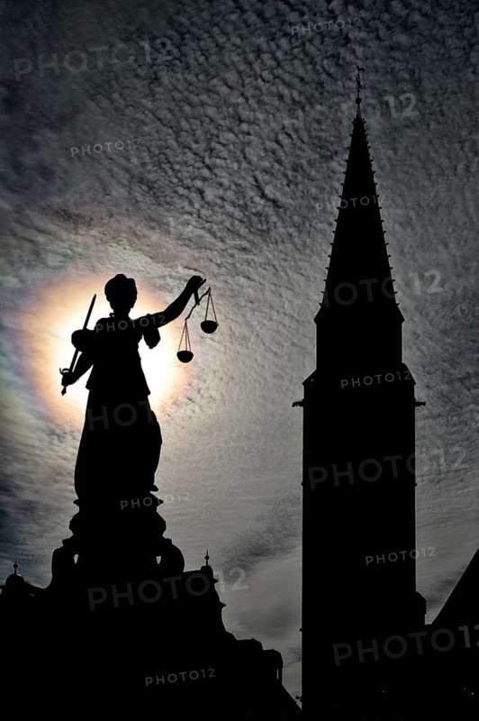Justitia statue in front of the silhouette of the Old St. Nicholas Church