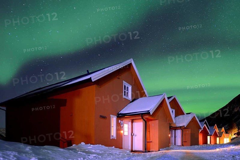 Red fishing huts in winter with Northern Lights