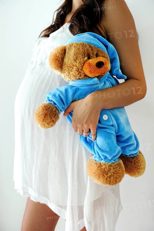 Woman with a pregnant belly holding a teddy bear
