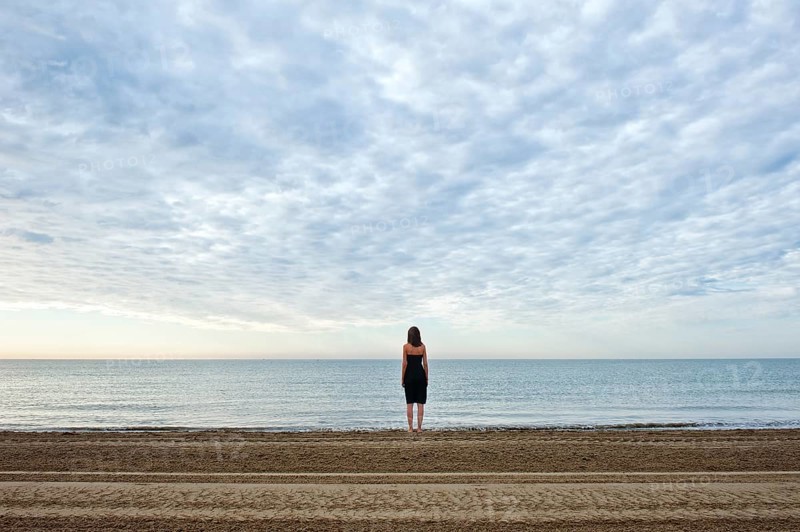 Woman wearing a black dress standing by the sea