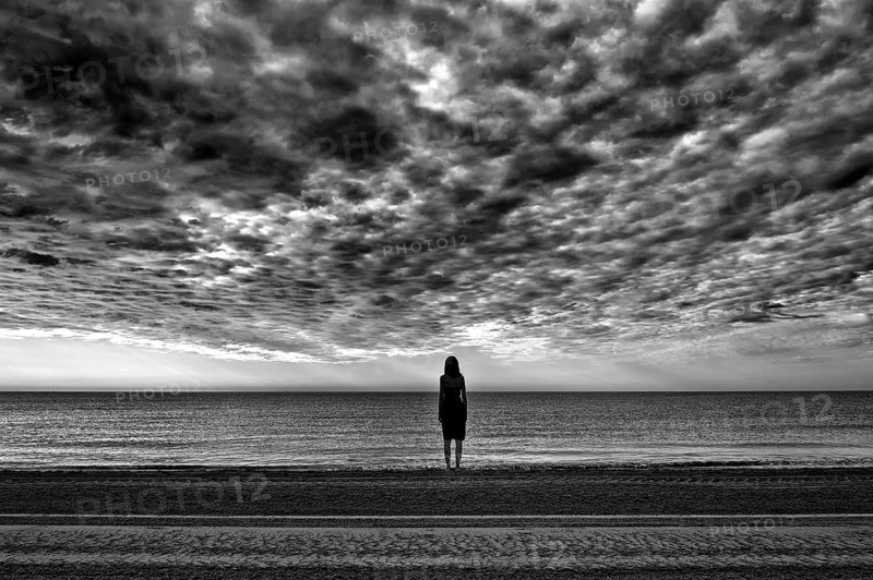 Woman wearing a black dress standing by the sea