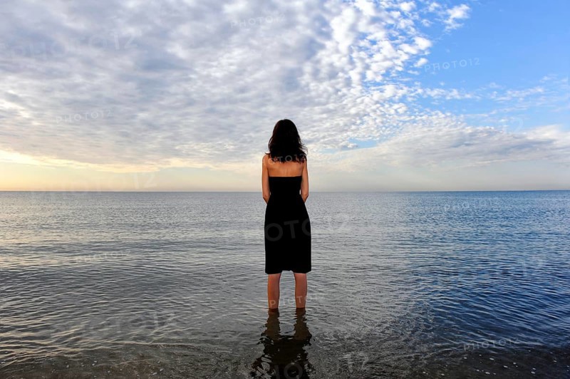 Woman wearing a black dress standing in the water of the sea