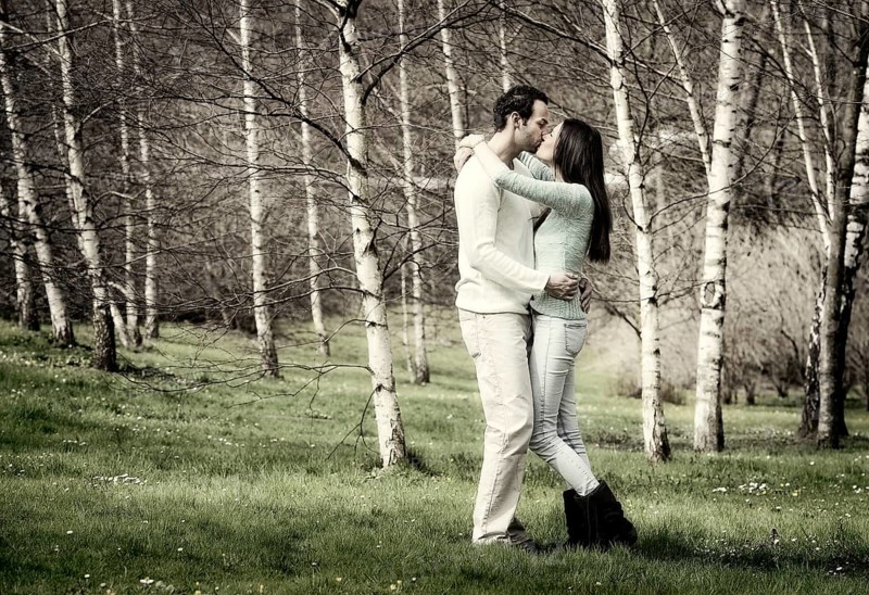 Young couple kissing in a birch forest