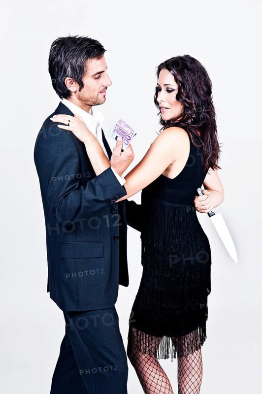 Man offering money to a woman who is holding a knife behind her back