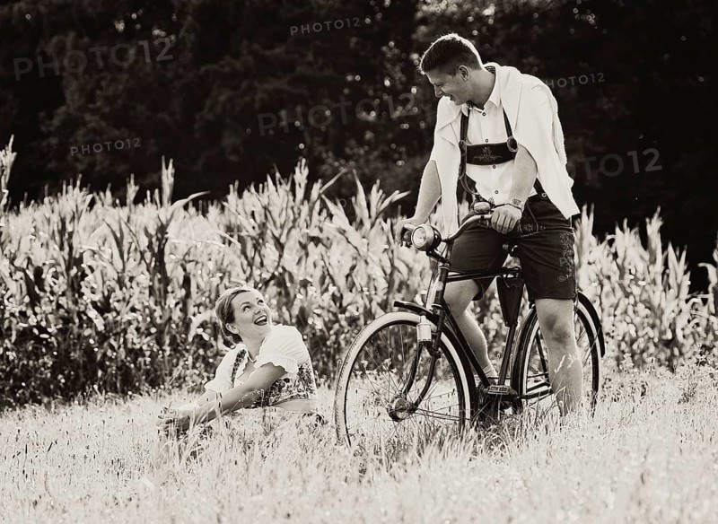 Man and a woman wearing traditional costume with an old bicycle within a natural landscape