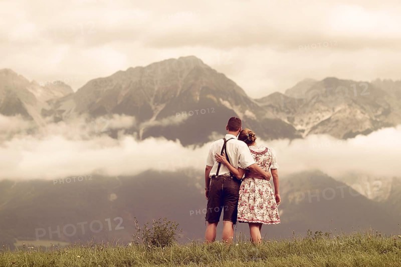 Man and a woman wearing traditional costume looking towards the mountains