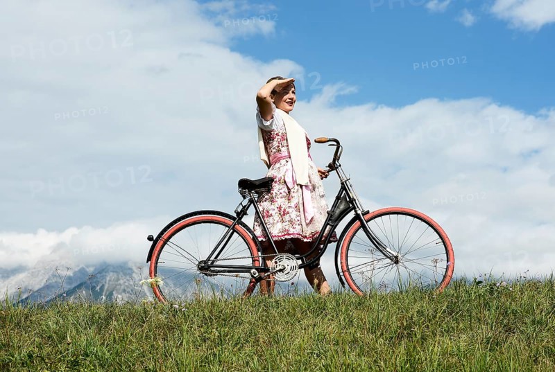 Woman wearing a dirndl with an old bicycle