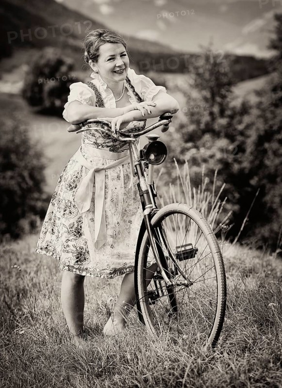Woman wearing a dirndl with an old bicycle