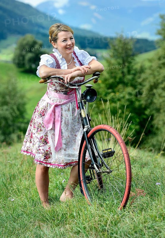 Woman wearing a dirndl with an old bicycle