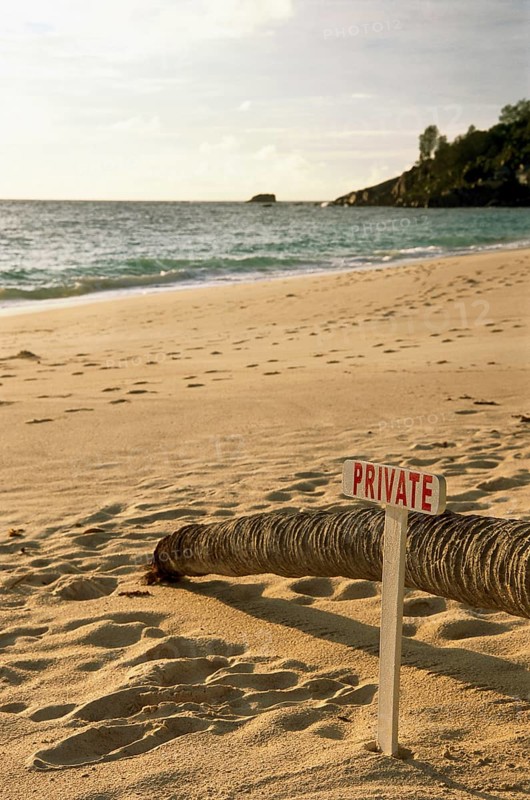 Deserted sandy beach with a wooden sign