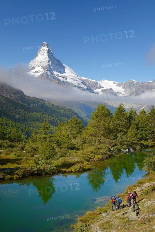 Hikers taking photographs of the Matterhorn with Lake Grindjisee in the foreground