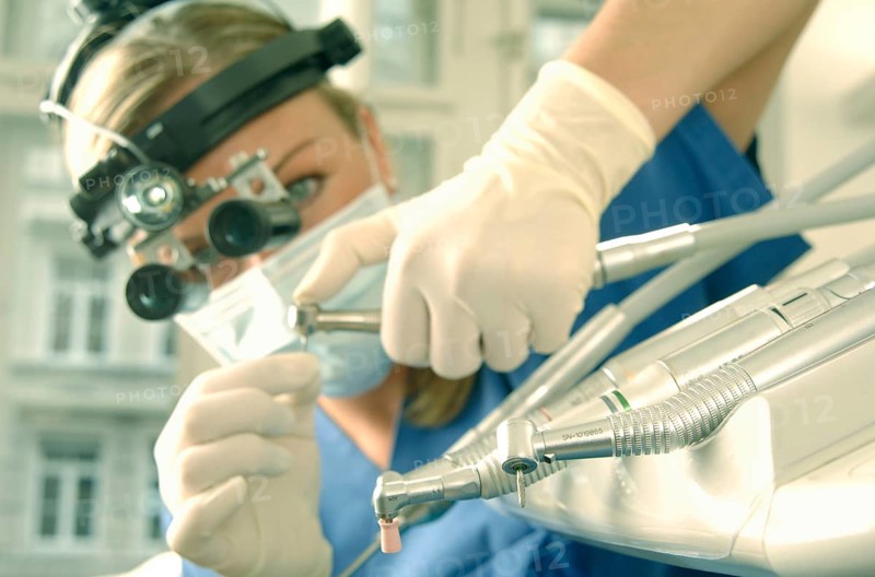 Dentist wearing magnifying loupes preparing a drill