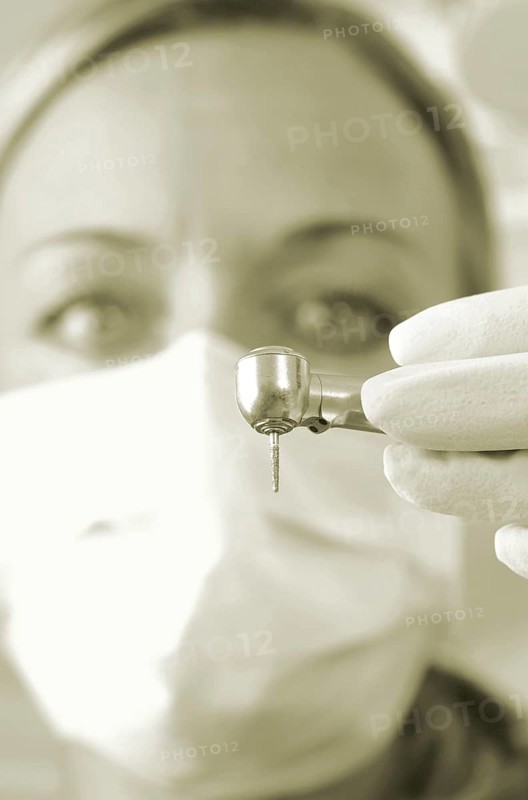 Dentist wearing a face mask and holding a drill