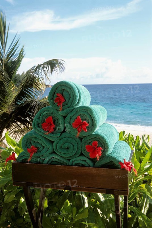 Stack of rolled towels with red flower on the beach