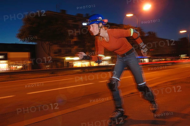 Woman on inline skates wearing a helmet and lights at night