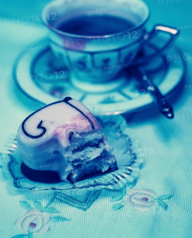 Half-eaten heart-shaped petit four and an old coffee cup