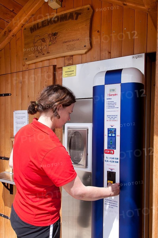 Woman extracting fresh milk from a milk vending machine in Novo Mesto