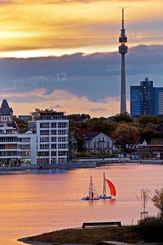 Two sailboats on Phoenix-See lake with Hoerder Burg Castle and Florian Tower at sunset