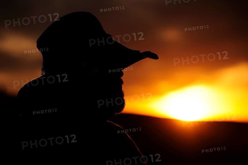 Silhouette of a cowboy in profile looking towards the sunset