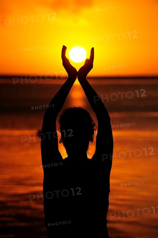 Woman holding the sun with both her hands
