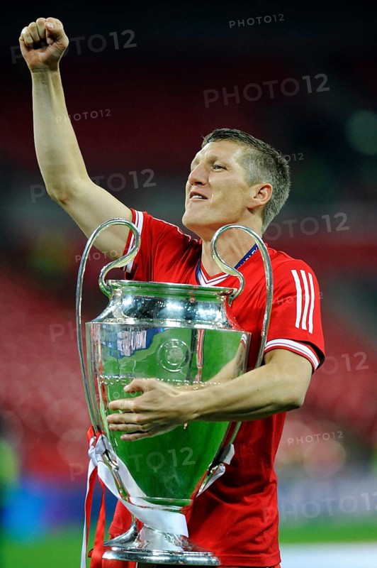Bastian Schweinsteiger cheering jubilantly while holding the trophy