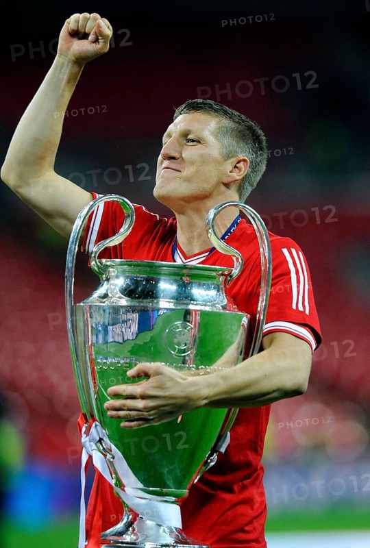 Bastian Schweinsteiger cheering jubilantly while holding the trophy