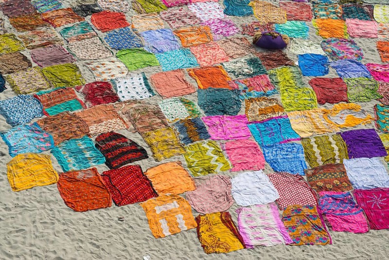 Colourful saris laying to dry after washing on a sandbank on the banks of the Yamuna River