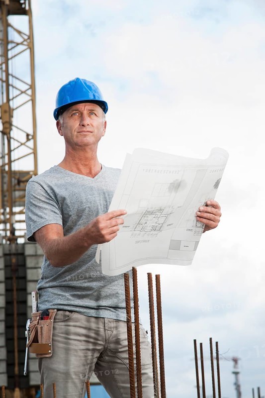 Construction worker wearing a hard hat and holding a building plan