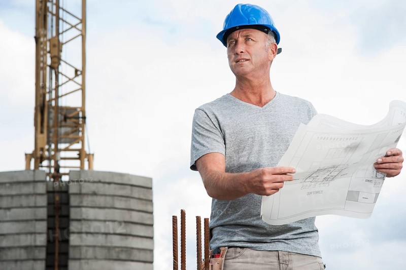 Construction worker wearing a hard hat and holding a building plan