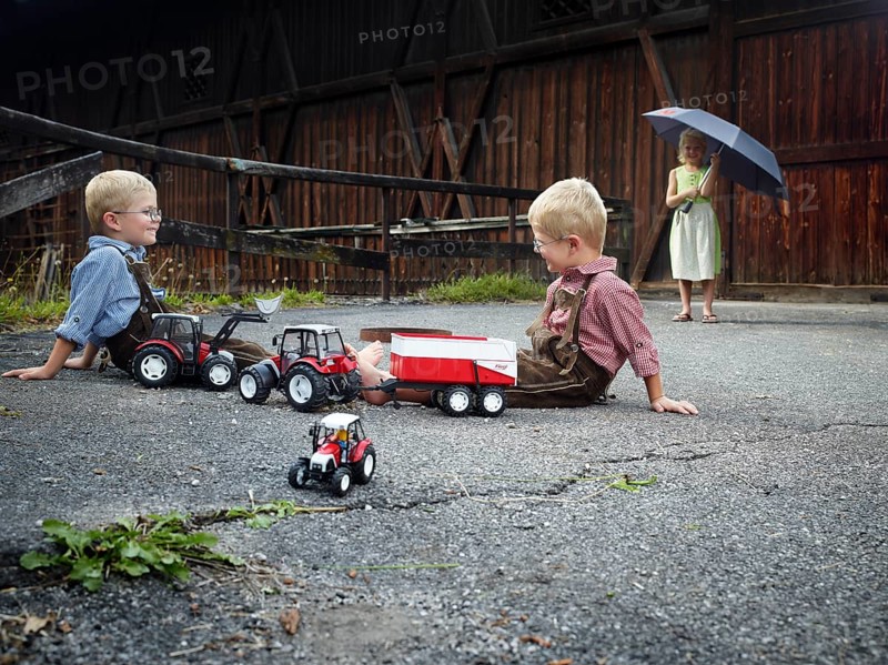 Children playing with toy tractors on farm