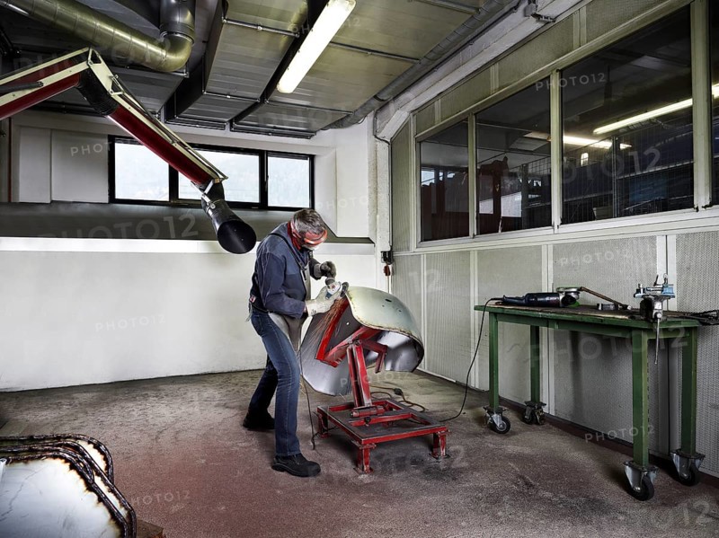 Worker grinding a fender in a workshop