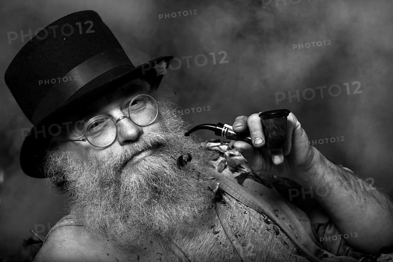 Elderly man with a long beard wearing a top hat and glasses