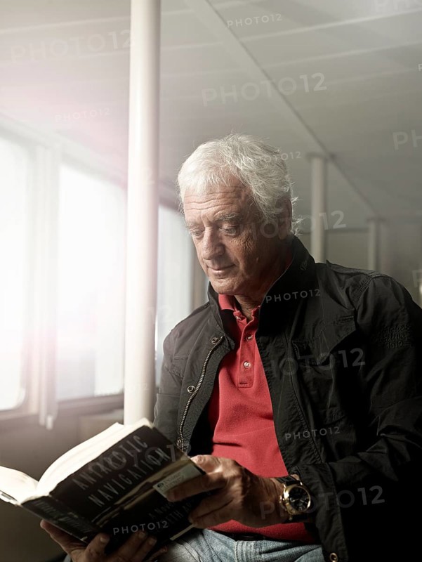 Elderly man reading a book on a ship