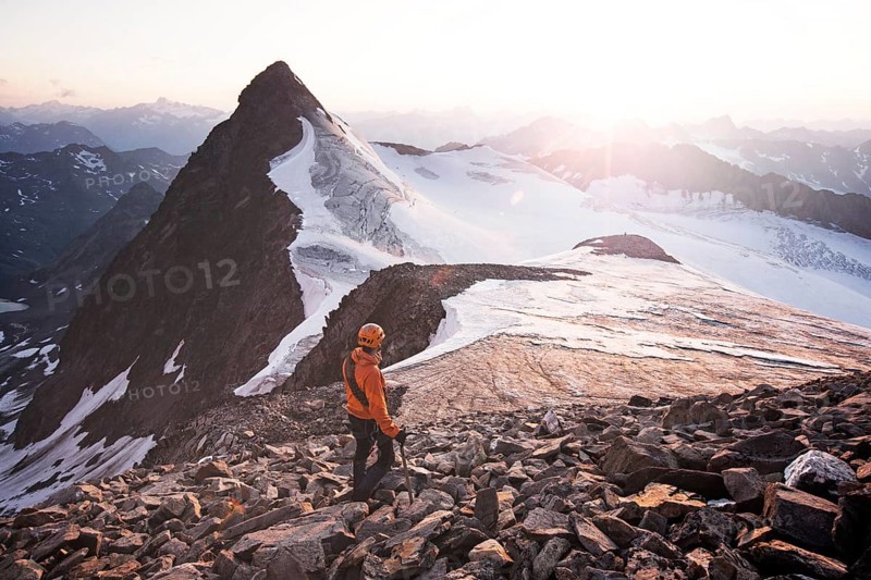 Mountain climber standing at the summit of Wilder Pfaff Mountain and looking towards the sunset