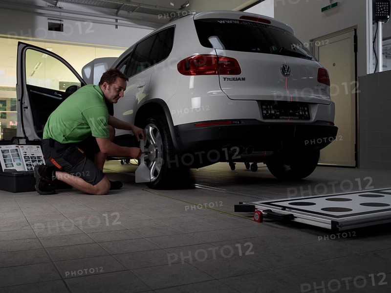 Car mechanic taking axis measurements with a laser