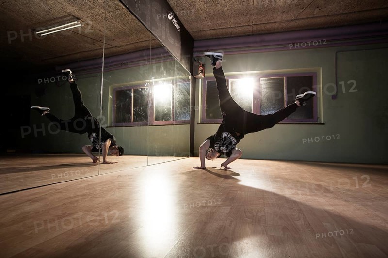 Breakdancer dancing in front of a mirror wall